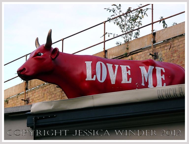 City Nature - urban cow - Life-sized red effigy of a cow with the words 'Love me' on a rooftop by the Borough Market in Southwark on the South Bank in London, UK. 