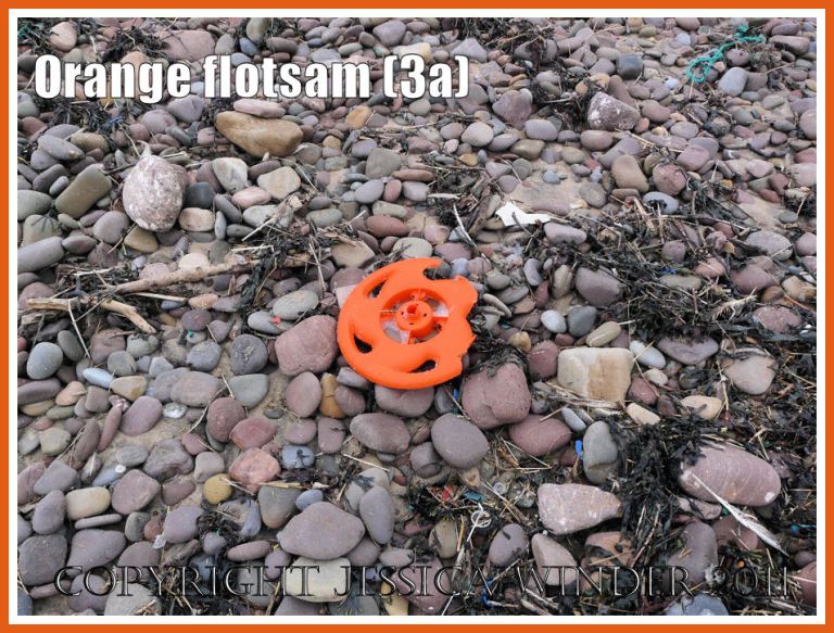 Orange flotsam: Context shot of an orange plastic wheel washed ashore onto the pebble strandline as flotsam (3a)