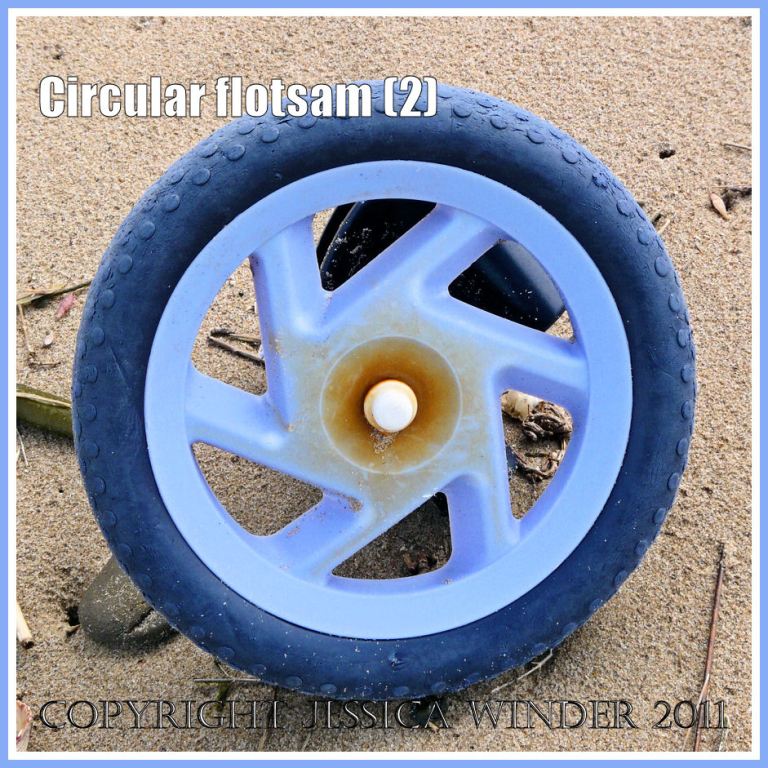 Circular flotsam; Blue buggy wheel on a sandy beach at Whiteford Sands, Gower, West Glamorgan (2)