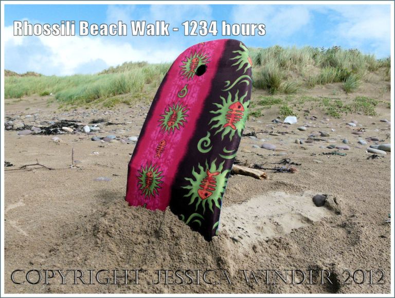 Rhossili Beach Walk - 1234 hours. Pink and green, fish pattern, body board flotsam stuck in the sand on Rhossili Beach, Gower, South wales, 22nd August 2012.