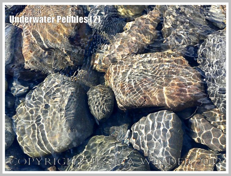 Underwater Pebbles (2) - Pebbles viewed through shallow river water with patterns of reflected sunlight from the water ripples, photographed on the beach in Neptune State Park, south of Yachats, Oregon, U.S.A.  