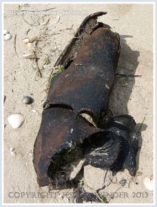 Old leather shoe washed ashore as flotsam on a sandy beach