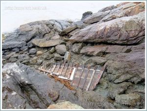 Outcrop of ancient volcanic rocks with boat wreck debris