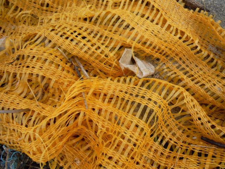 Yellow net bag flotsam on the beach