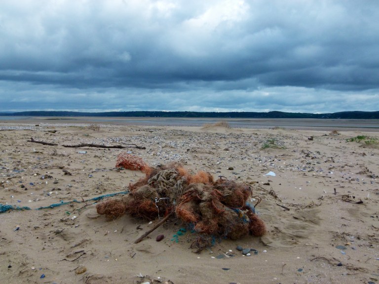 Pile of tangled fishing nets washed up on sandy beach