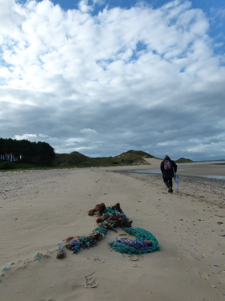 Rope & fishing net rubbish on a sandy shore strand line