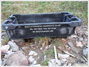 Black plastic crate with white writing on the strandline.