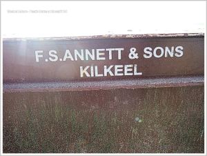 Brown plastic flotsam crate with white writing on a sandy beach