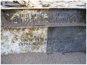 Detail of black and white fishing crate with black writing on beach