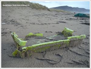 Broken yellow fishing crate on sandy beach