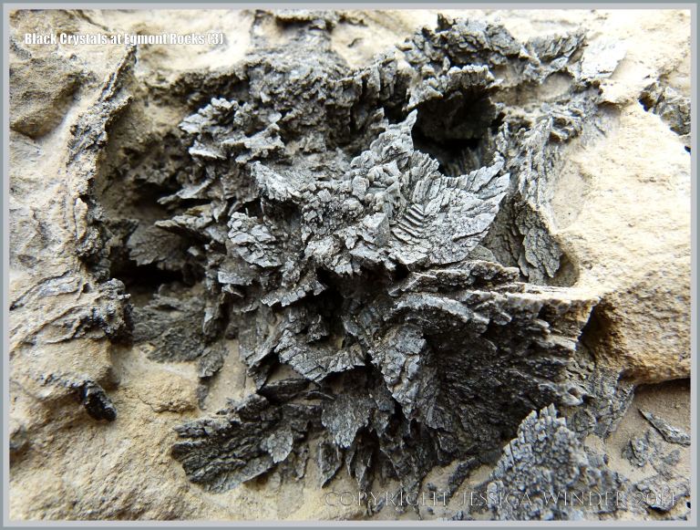 Black crystal formations in boulders on the beach