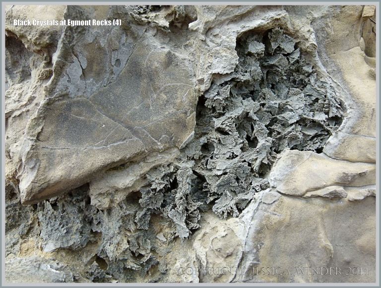 Black crystal formations in boulders on the beach