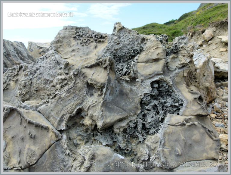 Black crystal formations in boulders on the beach