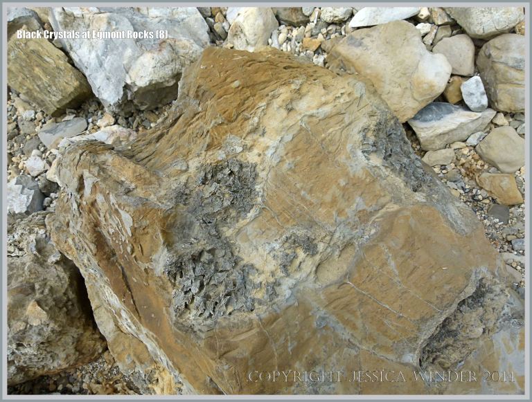 Black crystal formations in boulders on the beach