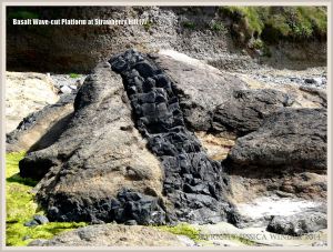 Linear dike of dark slowly-solidified basalt cutting through softer fragmental basalt on the Oregon Coast