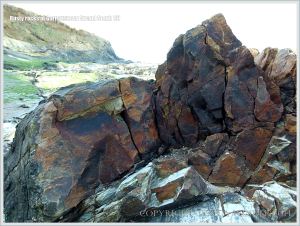 Dark rust-stained rocks on the beach