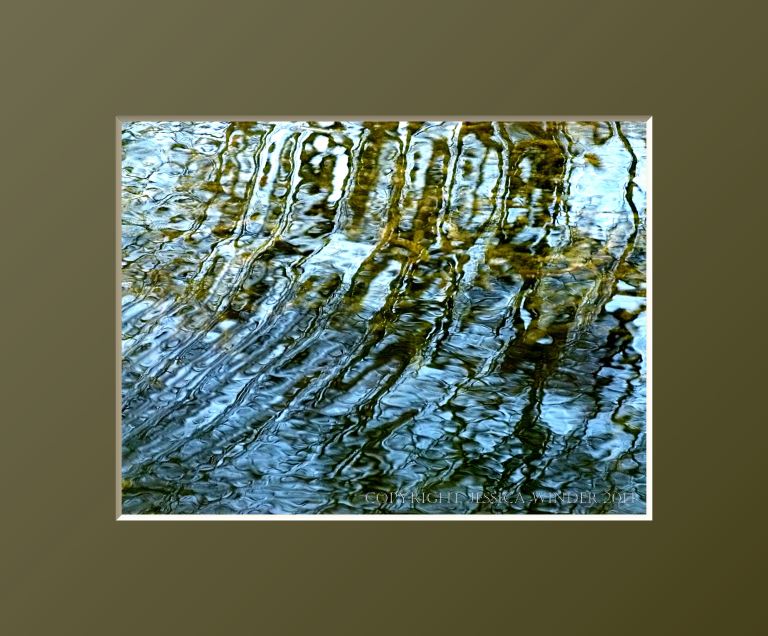 Natural abstract pattern of rippled reflections of trees in  a pond