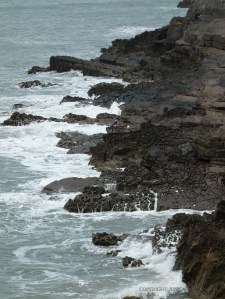 Jagged and eroded limestone fingers projecting into the sea at high tide in Mewslade Bay.