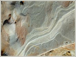 Pattern of weathered strata in grey rock in a beach boulder at Eype
