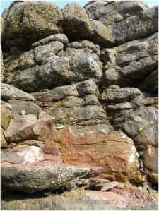 Bright orange patches are revealed on the Worms Head Causeway where rock has been smashed by winter storms