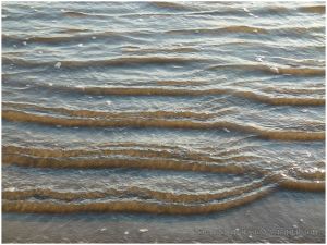 Gentle incoming waves at high tide on Rhossili beach