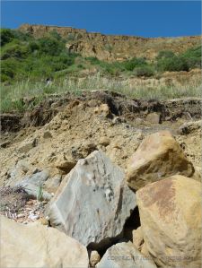 Sedimentary rock boulders on the seashore at the base of cliffs