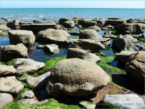Sedimentary rock boulders on the seashore extending into the sea