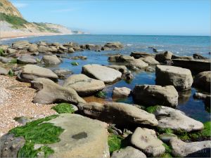 Sedimentary rock boulders on the seashore extending into the sea