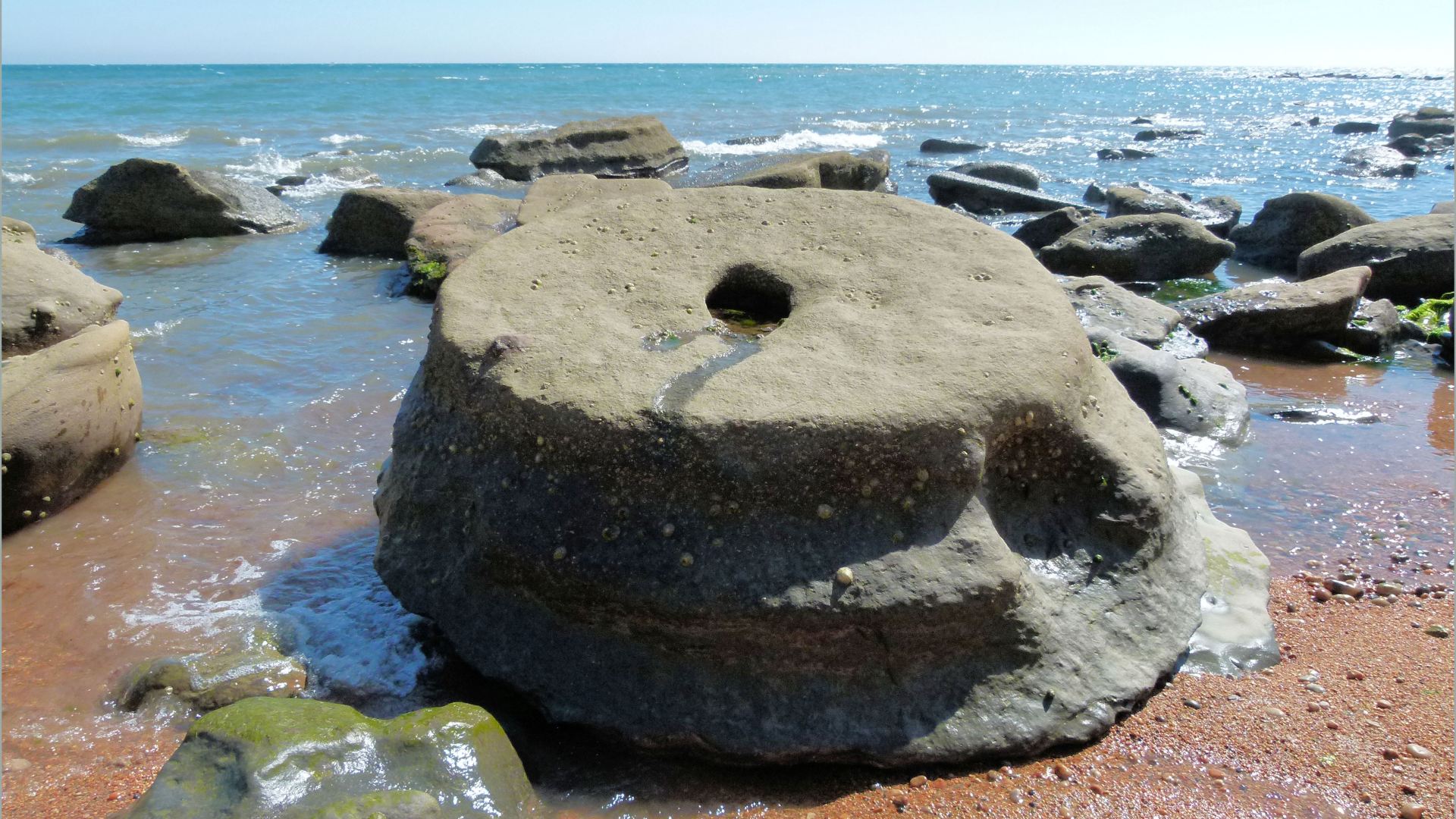 Sedimentary rock boulders on the seashore extending into the sea