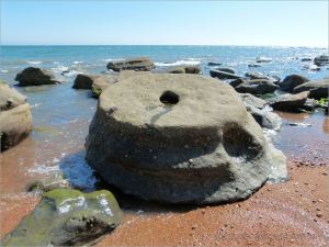 Sedimentary rock boulders on the seashore extending into the sea