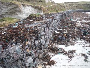 Rock-filled gabion sea defences protecting a tombola from erosion at Dogs Bay