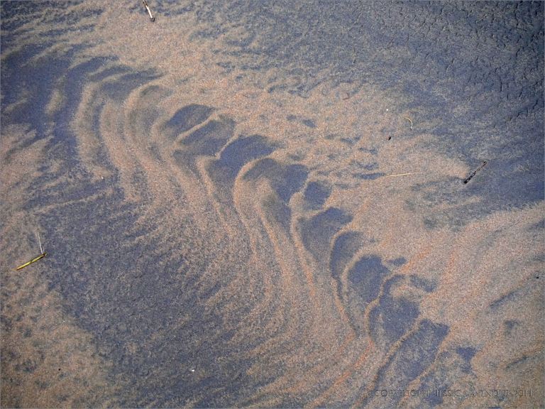 Two-tone sand patterns on a wintry beach beneath Rhossili Down on the Gower Peninsula