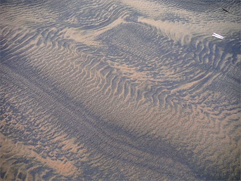 Two-tone sand patterns on a wintry beach beneath Rhossili Down on the Gower Peninsula
