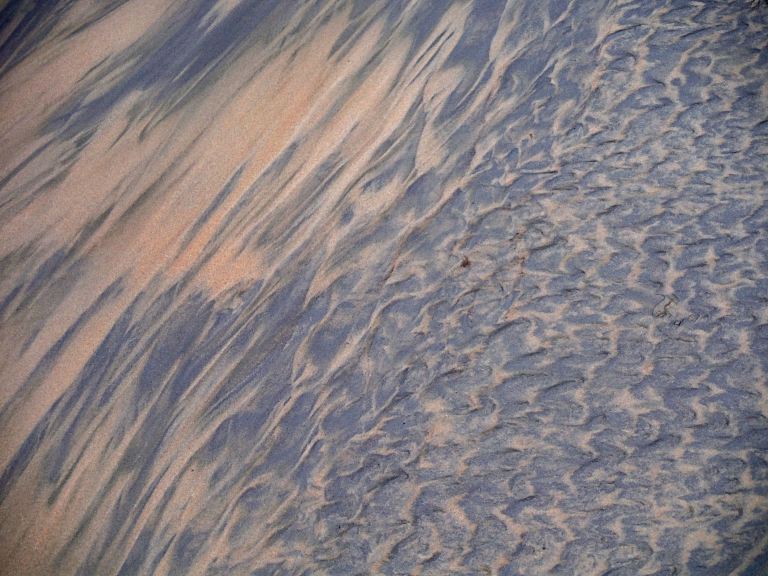 Two-tone sand patterns on a wintry beach beneath Rhossili Down on the Gower Peninsula