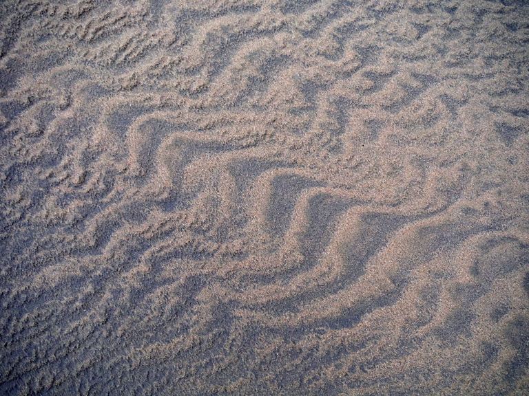 Two-tone sand patterns on a wintry beach beneath Rhossili Down on the Gower Peninsula