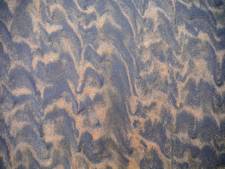 Two-tone sand patterns on a wintry beach beneath Rhossili Down on the Gower Peninsula