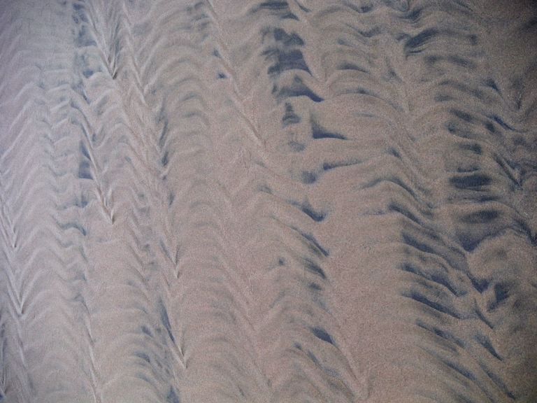 Two-tone sand patterns on a wintry beach beneath Rhossili Down on the Gower Peninsula