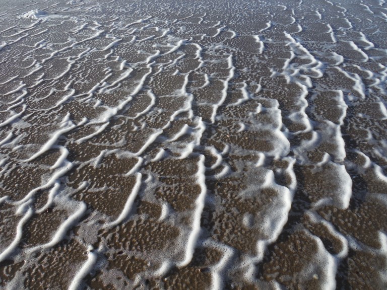 Natural patterns of sea foam driven by high winds at Rhossili