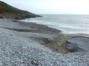 Two streams of water running from the base of shingle banks into the sea