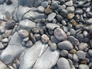Pebbles at the water's edge in Pwll Du Bay