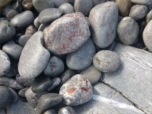 Pebbles at the water's edge in Pwll Du Bay
