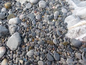Pebbles at the water's edge in Pwll Du Bay