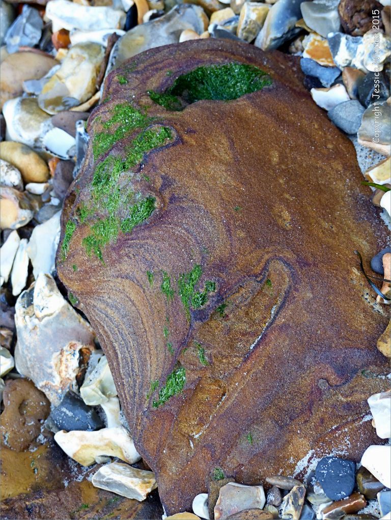 Beach boulder and pebbles on the north side of Redend Point in Studland Bay, Dorset, England.