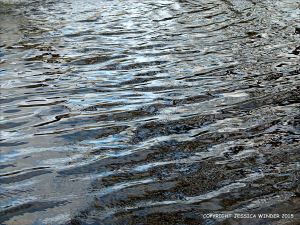 Natural water reflection patterns and textures in the rippled surface of a fountain bowl