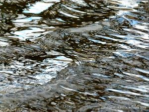 Natural water reflection patterns and textures in the rippled surface of a fountain bowl