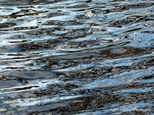 Natural water reflection patterns and textures in the rippled surface of a fountain bowl