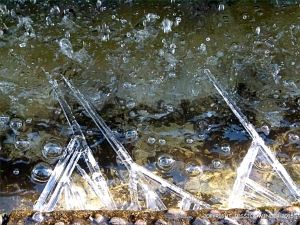 Large ice crystals growing in a triangular formation on the edge of a fountain
