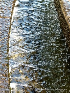 Large ice crystals growing in a triangular formation on the edge of a fountain