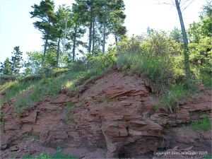 Low cliff of red Permian rock on the shore at Lord Selkirk Provincial Park in Prince Edward Island