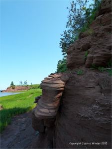 View along the shoreline at Lord Selkirk Provincial Park in Prince Edward Island, Canada, with lush green early summer vegetation and red Permian rock strata.
